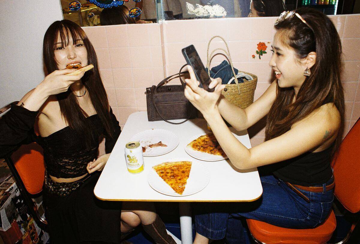 Two people eating pizza at a table